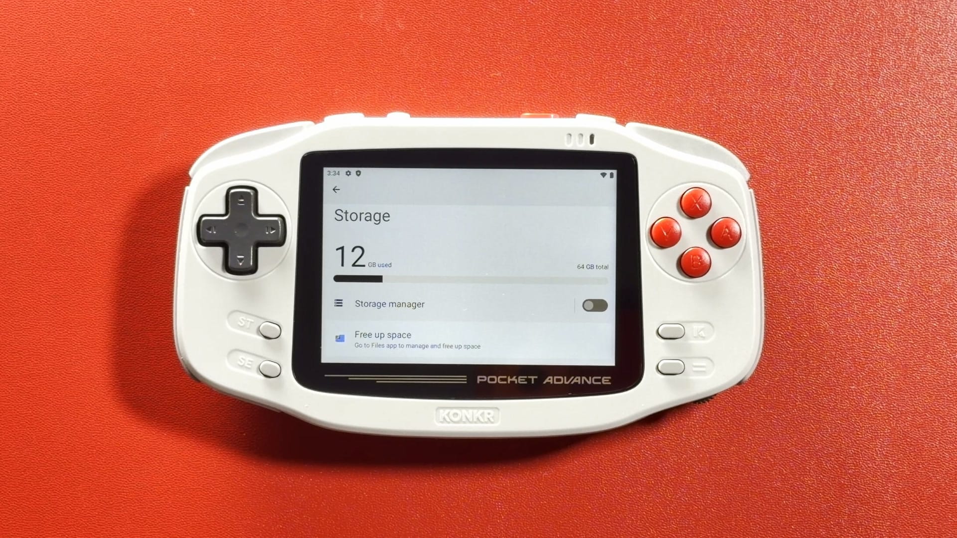 The KONKR Pocket Advance on a red table showing its Storage screen with 12 GB used of 64 GB