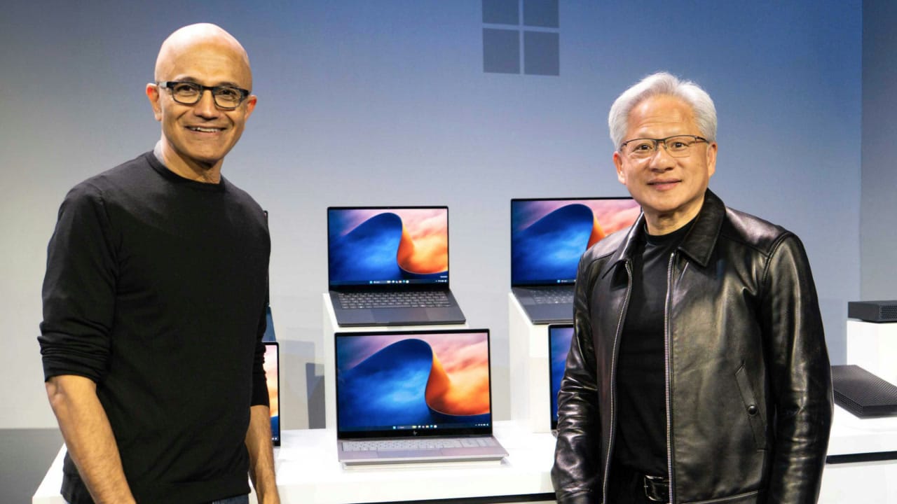 Satya Nadella and Jensen Huang standing in front of RTX Spark laptops at Microsoft’s October 7 event