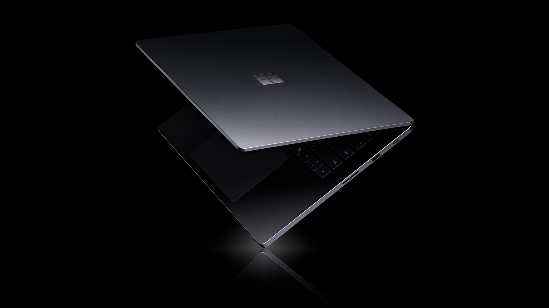 A black Microsoft Surface Laptop Ultra, half open, on a black background