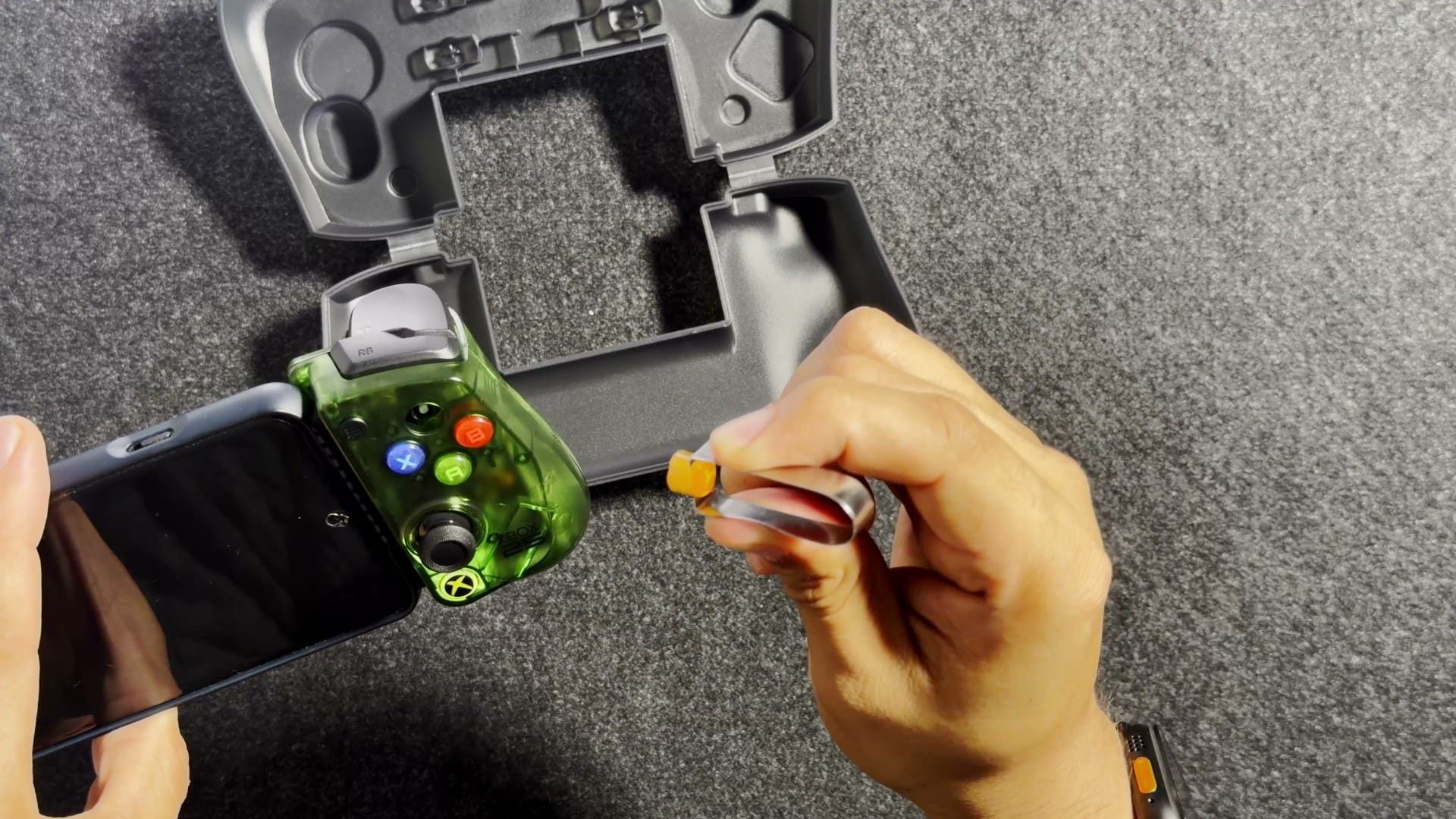 A face button being pulled from the X5 Lite with the included clip, next to the storage case