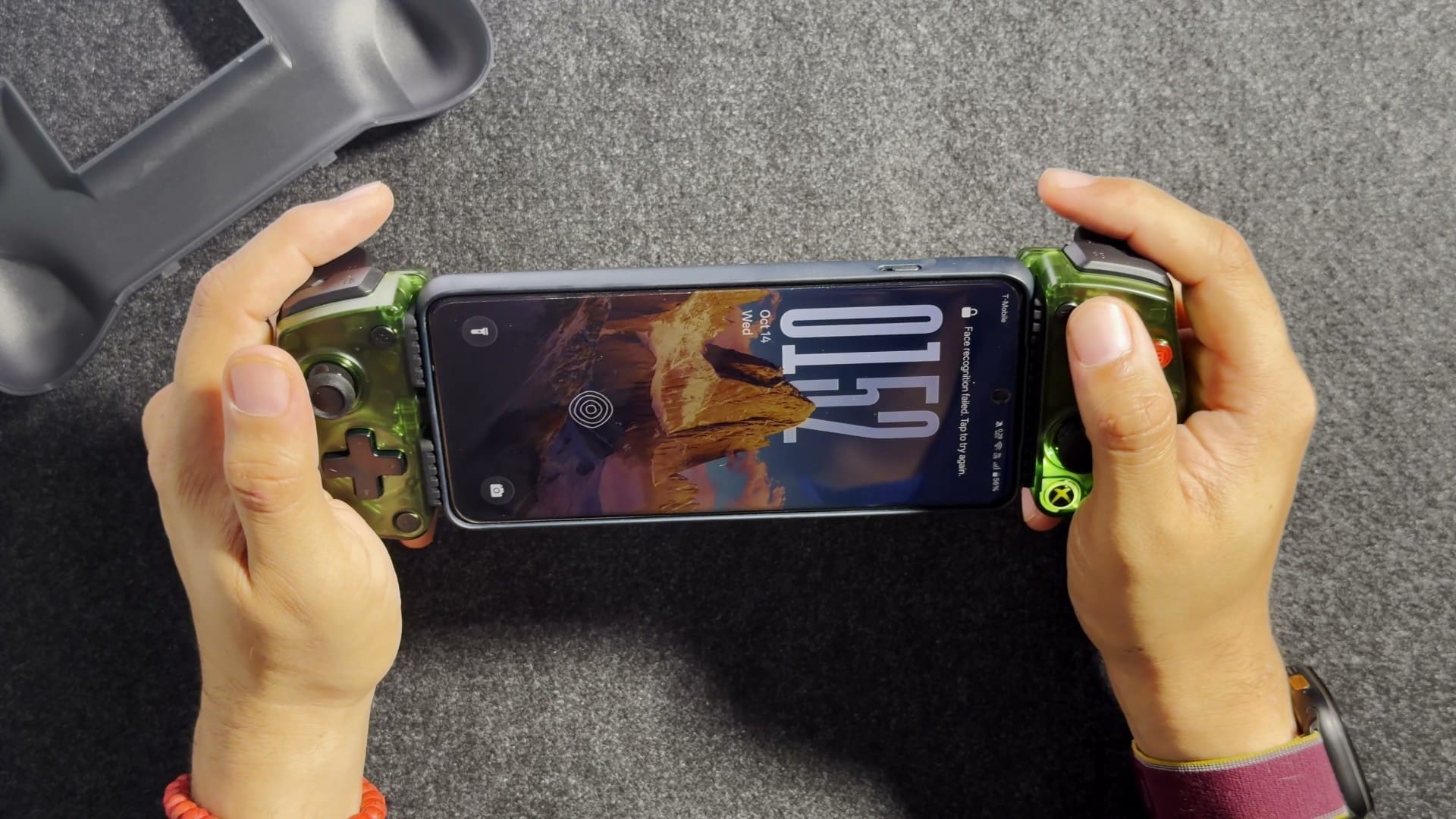 Two hands holding the X5 Lite with an Android phone showing its lock screen