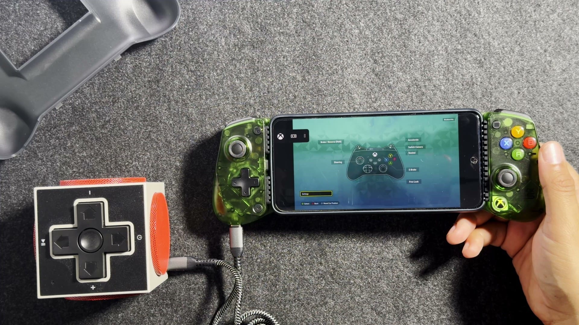 A USB-C speaker cabled into the port on the left grip of the X5 Lite, with a phone inside