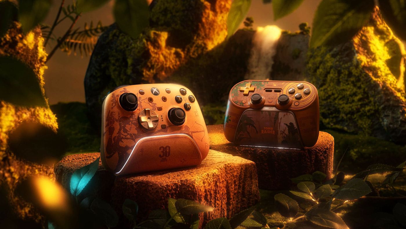 The gold Tomb Raider edition of the 8BitDo Ultimate 3 and the Lost Valley edition of the 8BitDo Pro 3 on their docks, on stone blocks in a jungle set with a waterfall