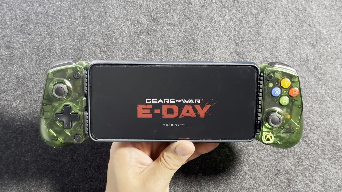 The GameSir X5 Lite for XBOX in translucent green holding a phone that shows the Gears of War: E-Day title screen