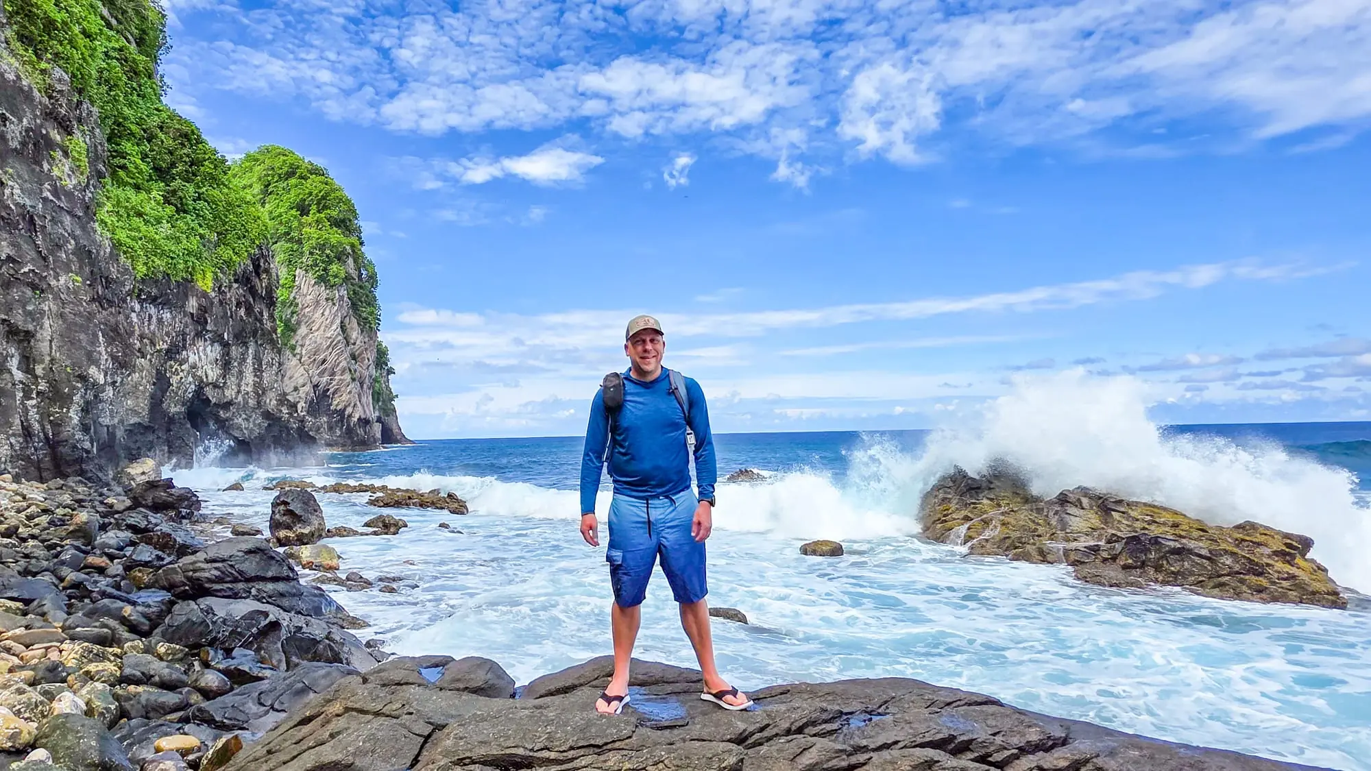 Eric Kufrin standing on rocky coastline with crashing waves and sea stacks, celebrating completion of all 63 National Parks