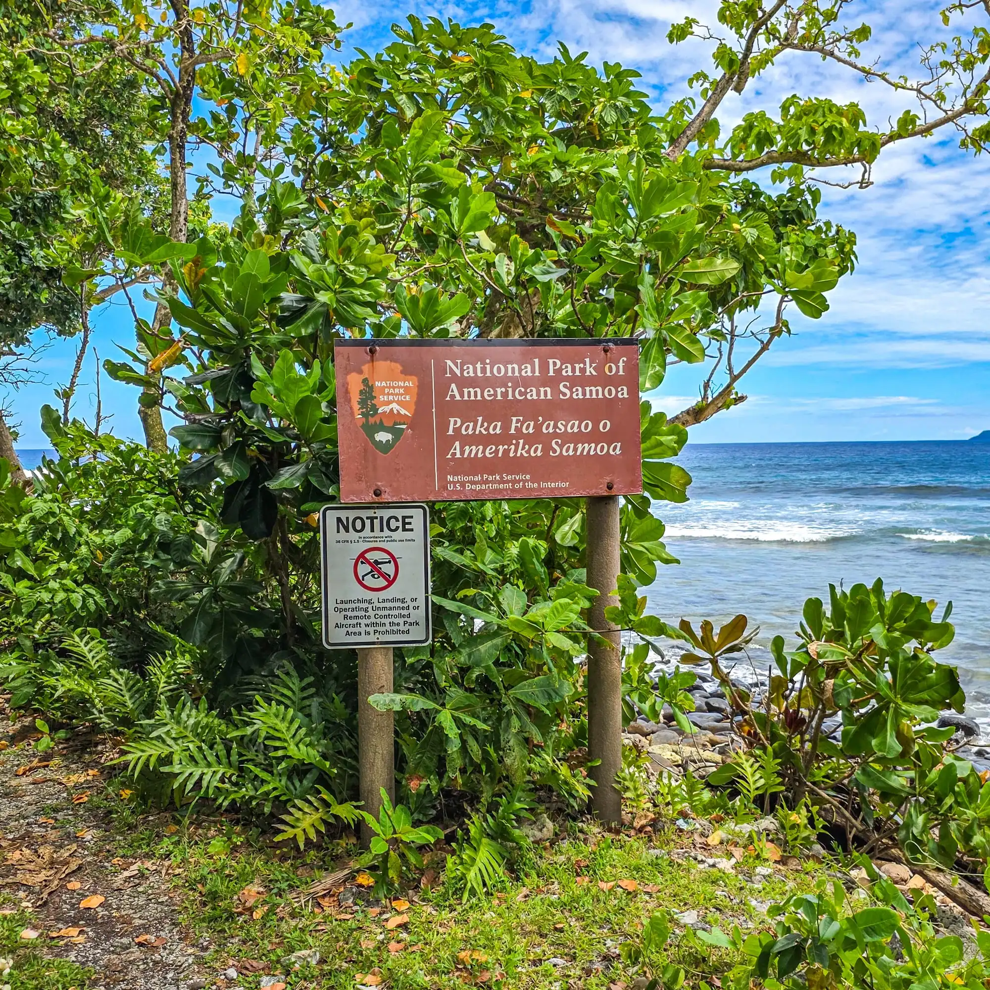 National Park of American Samoa entrance sign with ocean waves and tropical vegetation at the 63rd national park