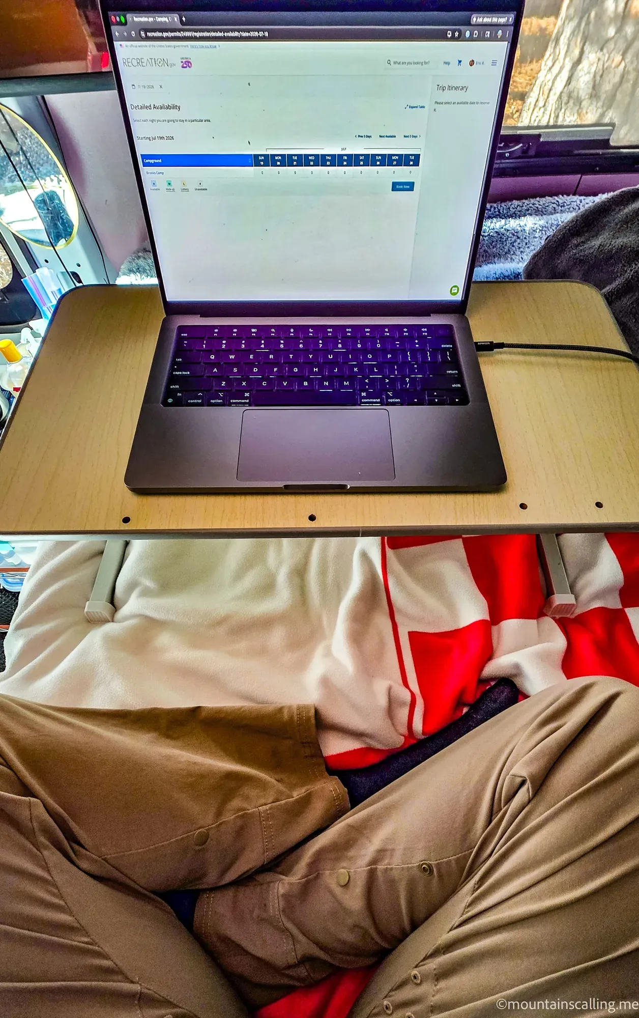 Laptop displaying Recreation.gov reservation page on wooden table, preparing for 9 AM park permit booking
