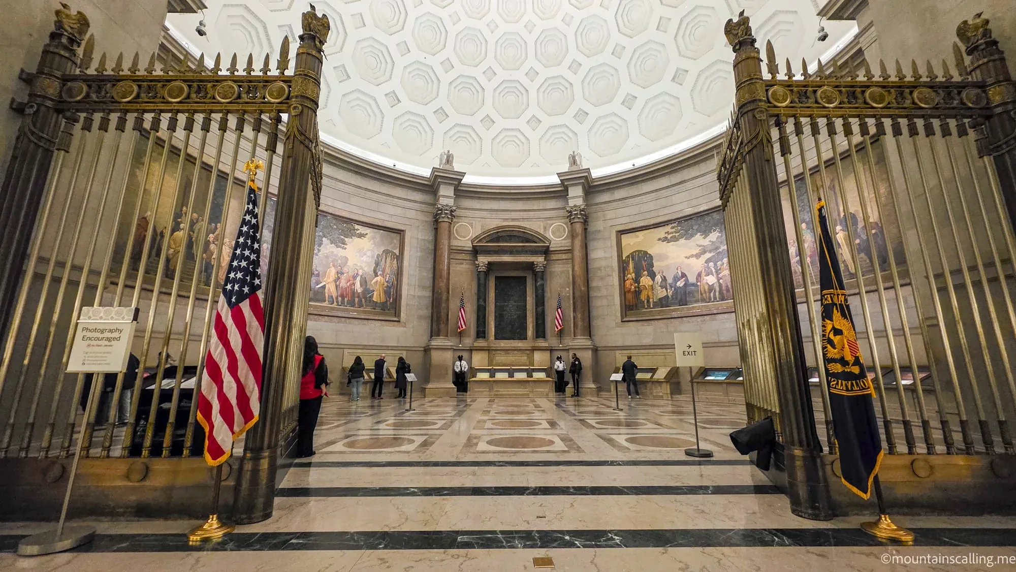 Interior of the National Archives Rotunda for the Charters of Freedom showing ornate columns, domed ceiling, and visitors viewing founding documents