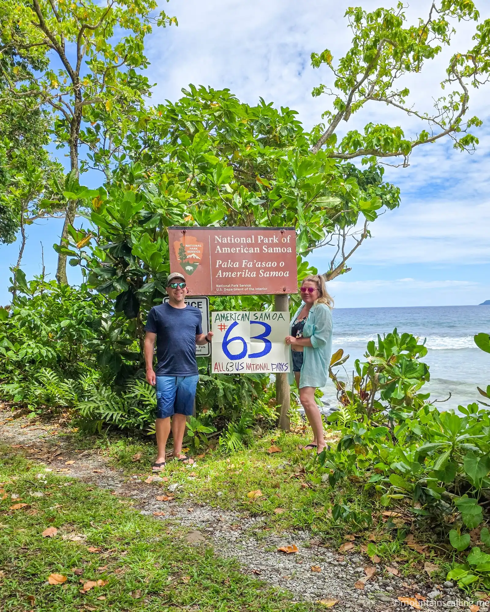 Eric Kufrin and Valerie standing beside National Park of American Samoa entrance sign with handmade #63 all US national parks completion sign