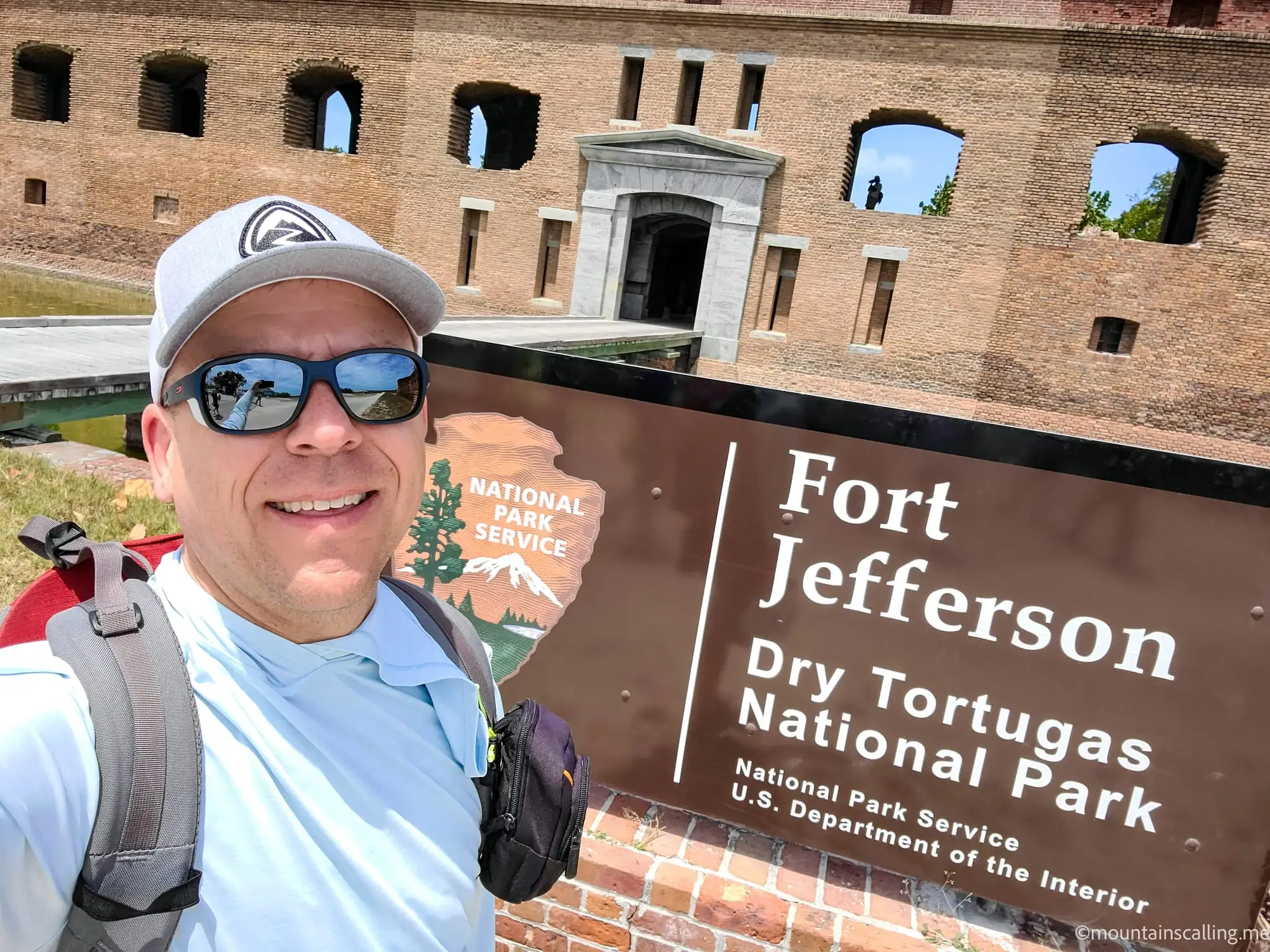 Eric Kufrin taking a selfie at Fort Jefferson entrance sign in Dry Tortugas National Park with historic brick fort walls in background