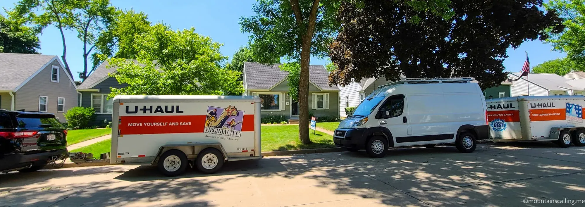 U-Haul trailer and moving van parked in residential driveway, preparing for cross-country move to California