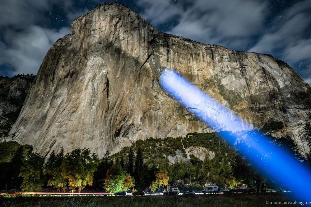 Night photography of granite cliff face with blue flashlight beam illuminating rock formation called Sea of Dreams under starry sky