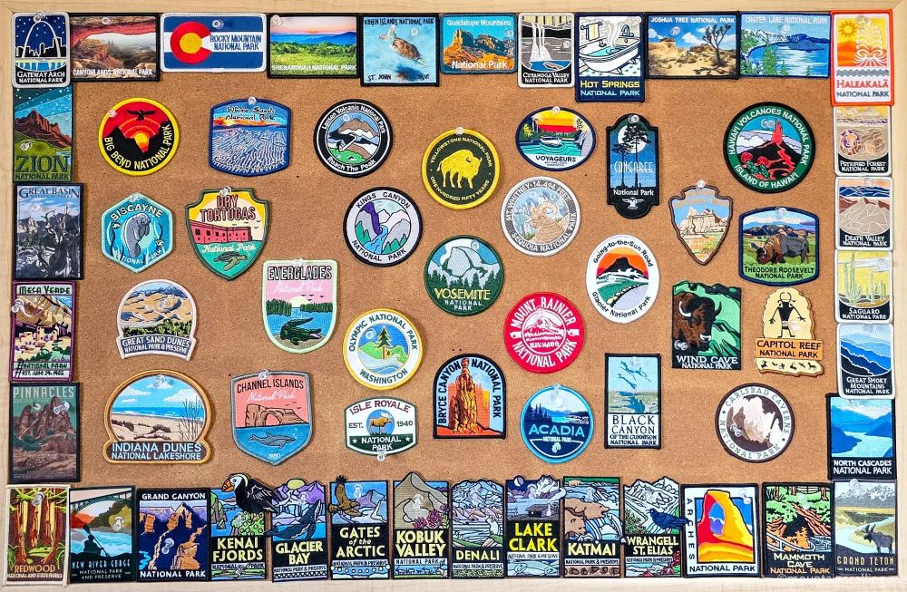 Collection of National Park patches and stickers displayed on cork board showing 62 of 63 US National Parks visited
