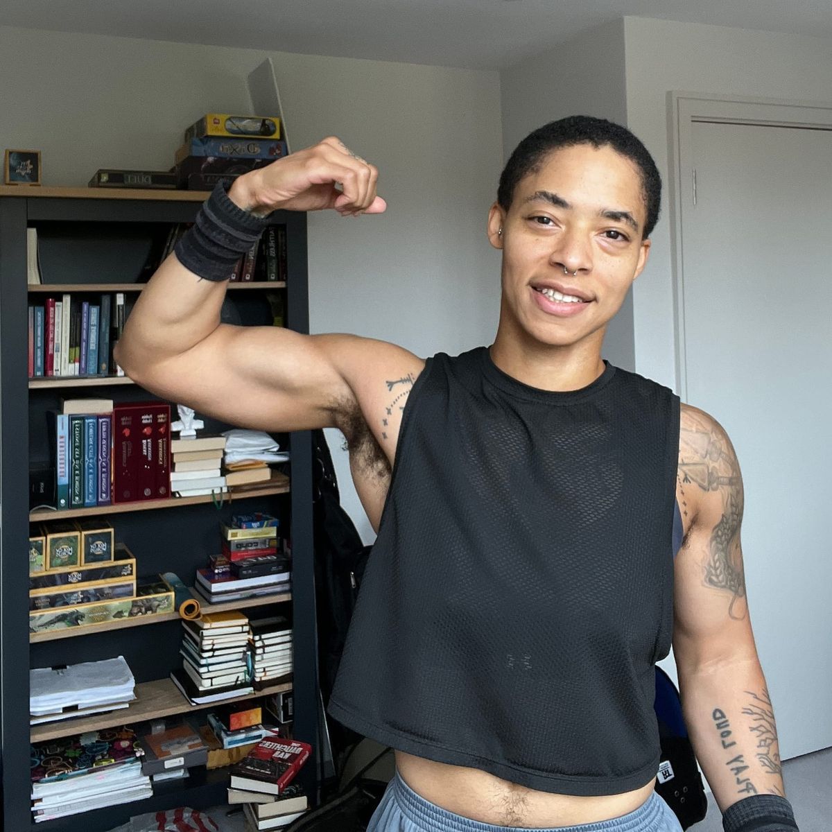 c. l. clark flexing their good arm in front of a book shelf. the muscle is very large, thank you very much.