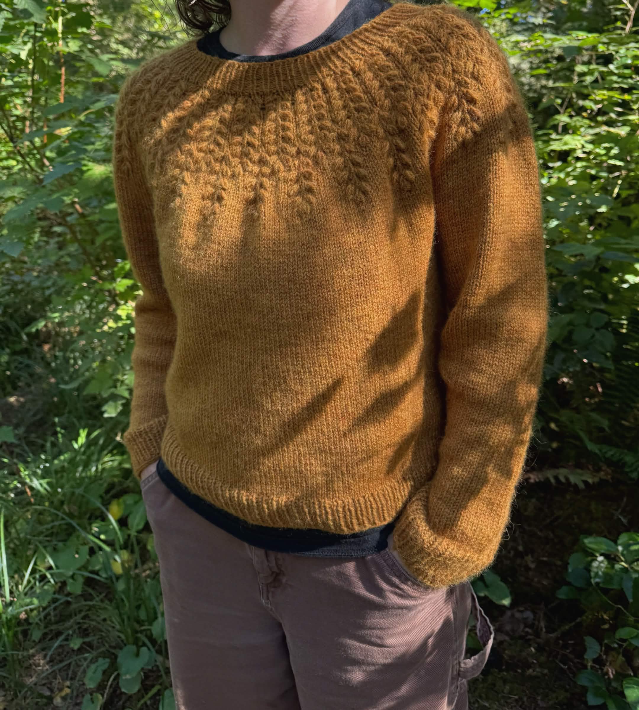 a person (me) in a gold yellow sweater with wheat/grain-like cabling along the yoke.