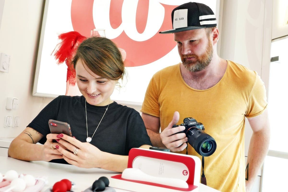 Fotograf a klientka stojí v minimalistickém showroomu Whoop·de·doo a společně si prohlížejí nafocené produkty na displeji fotoaparátu.