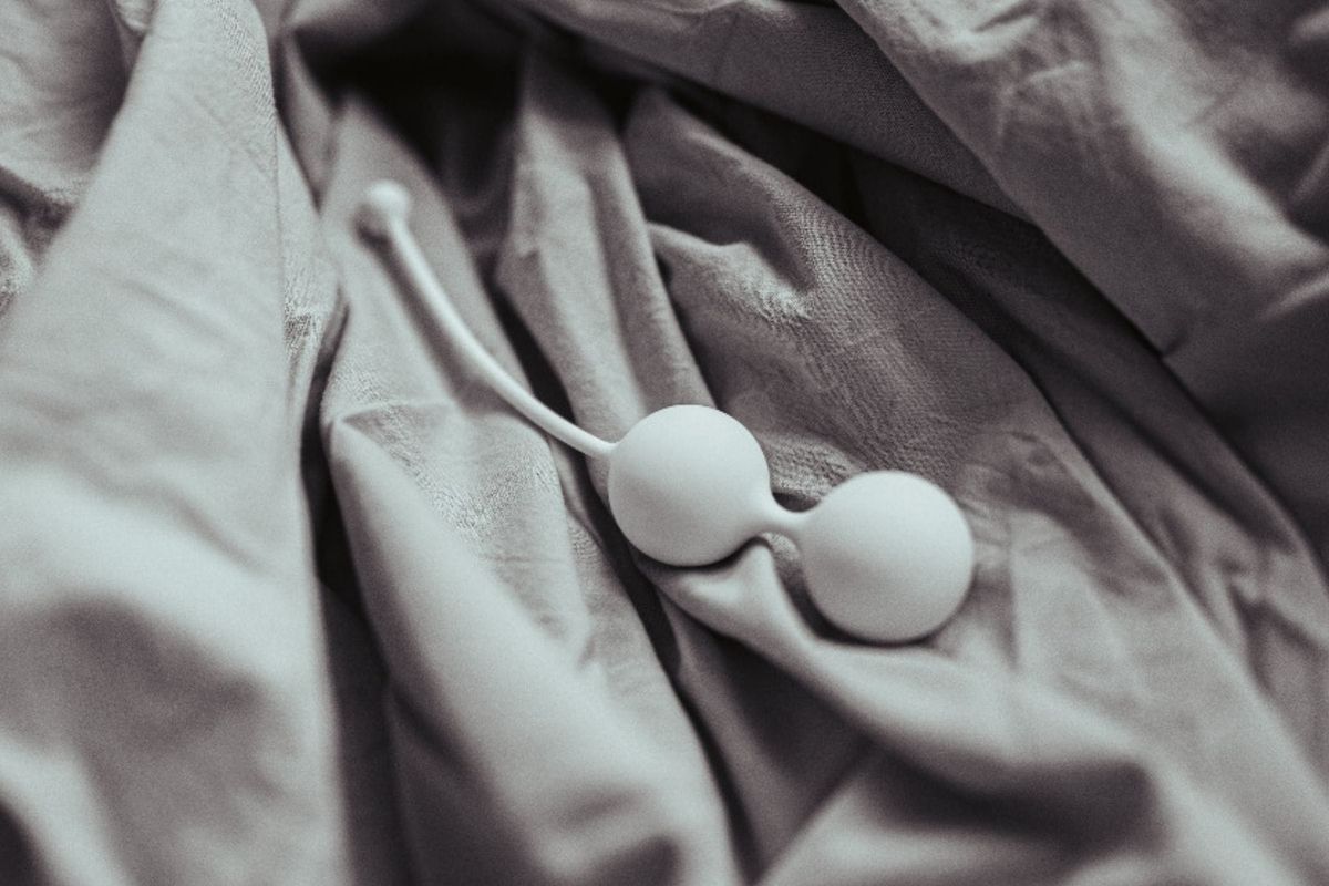Černobílý detailní záběr na bílé venušiny kuličky Whoop·de·doo položené na zmačkané šedé látce. Snímek zdůrazňuje texturu a minimalistický design.