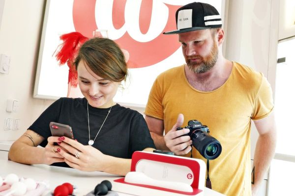 Fotograf a klientka stojí v minimalistickém showroomu Whoop·de·doo a společně si prohlížejí nafocené produkty na displeji fotoaparátu.