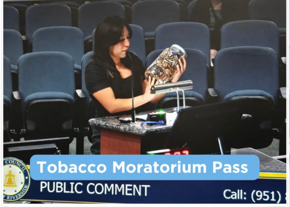A woman holds up a large jar filled with cigarette butts and litter at a podium during a Riverside City Council public comment session, with a "Tobacco Moratorium Pass" banner visible on screen.