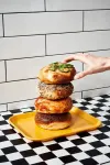 Four house-made New York-style bagels stacked on a yellow tray at Mikey G's in Midtown Riverside: jalapeño, everything, cheese-topped and plain, against white subway tile.