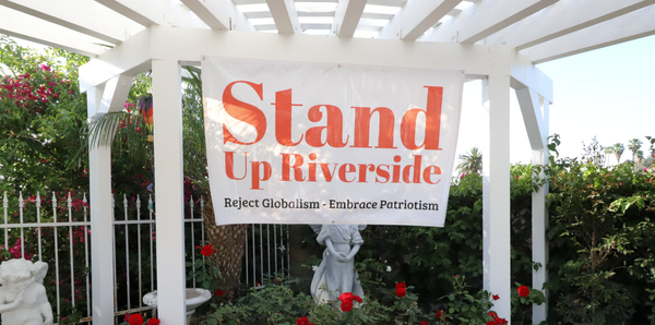 A red and white banner for the political group, Stand Up Riverside