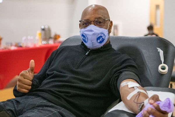 A man gives a thumbs up while donating blood.