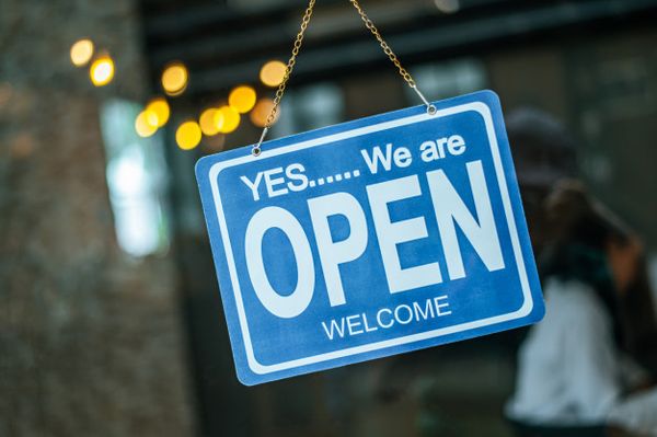 A photo of an OPEN sign outside a a business window.