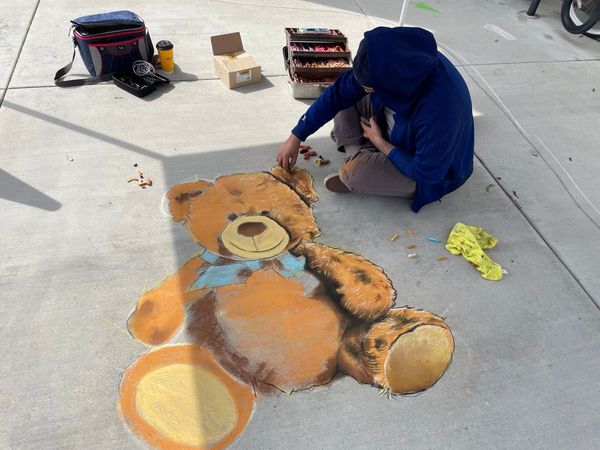 Photo of local Riverside artist coloring a realistic chalk drawing