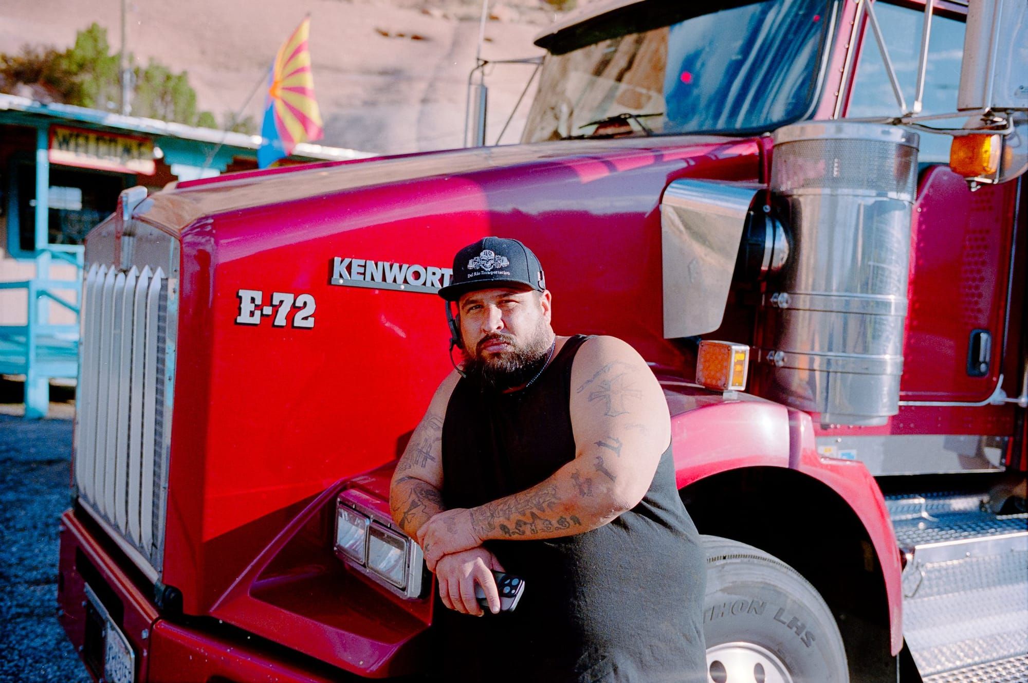 A driver standing by his red Kenworth truck