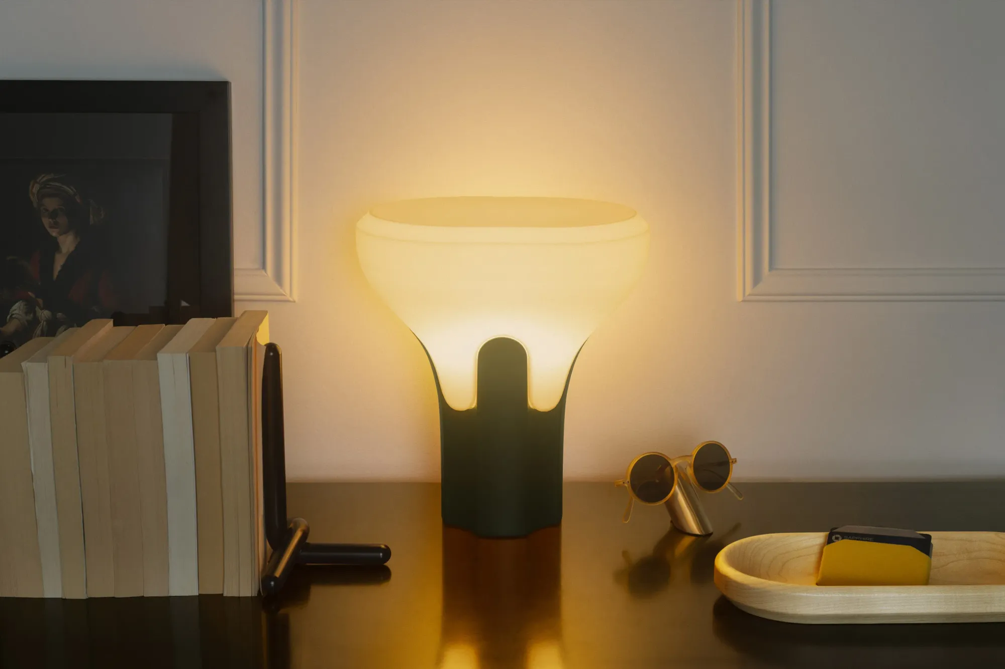 A ‘Flux Table Light’ from Gantri illuminates a home office table filled with books and some knick-knacks