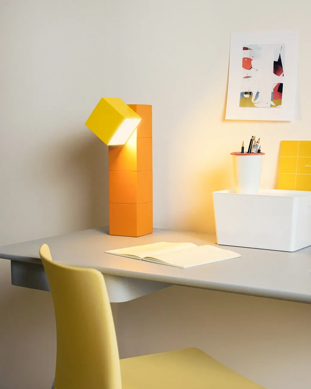 Gantri’s Analog Task Light table lamp is placed on a home office table along with an open blank journal and a pen holder filled with pencils