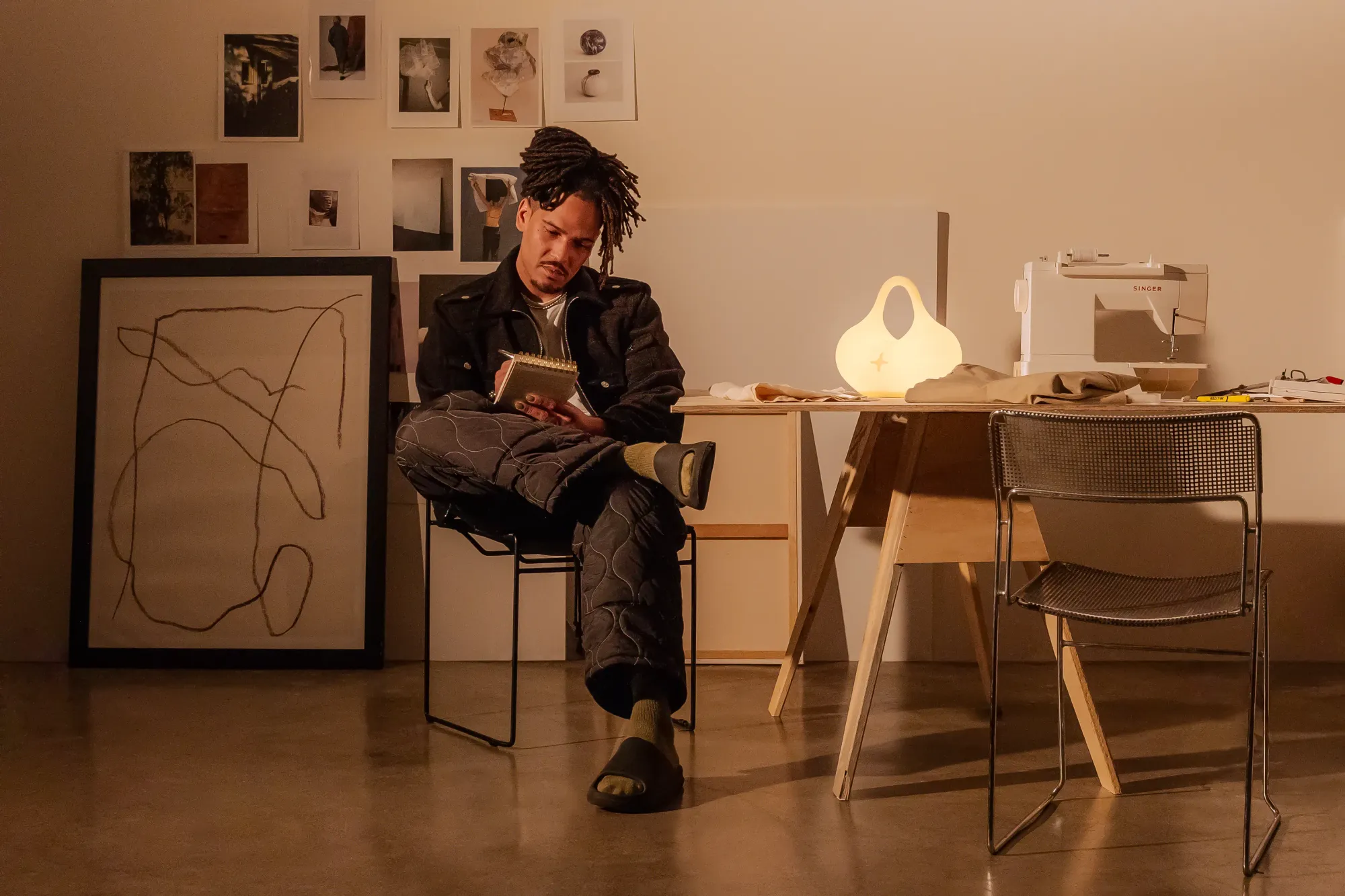 A man is seated at his home office table. A Gantri Bag Light is on the table, lighting up the scene