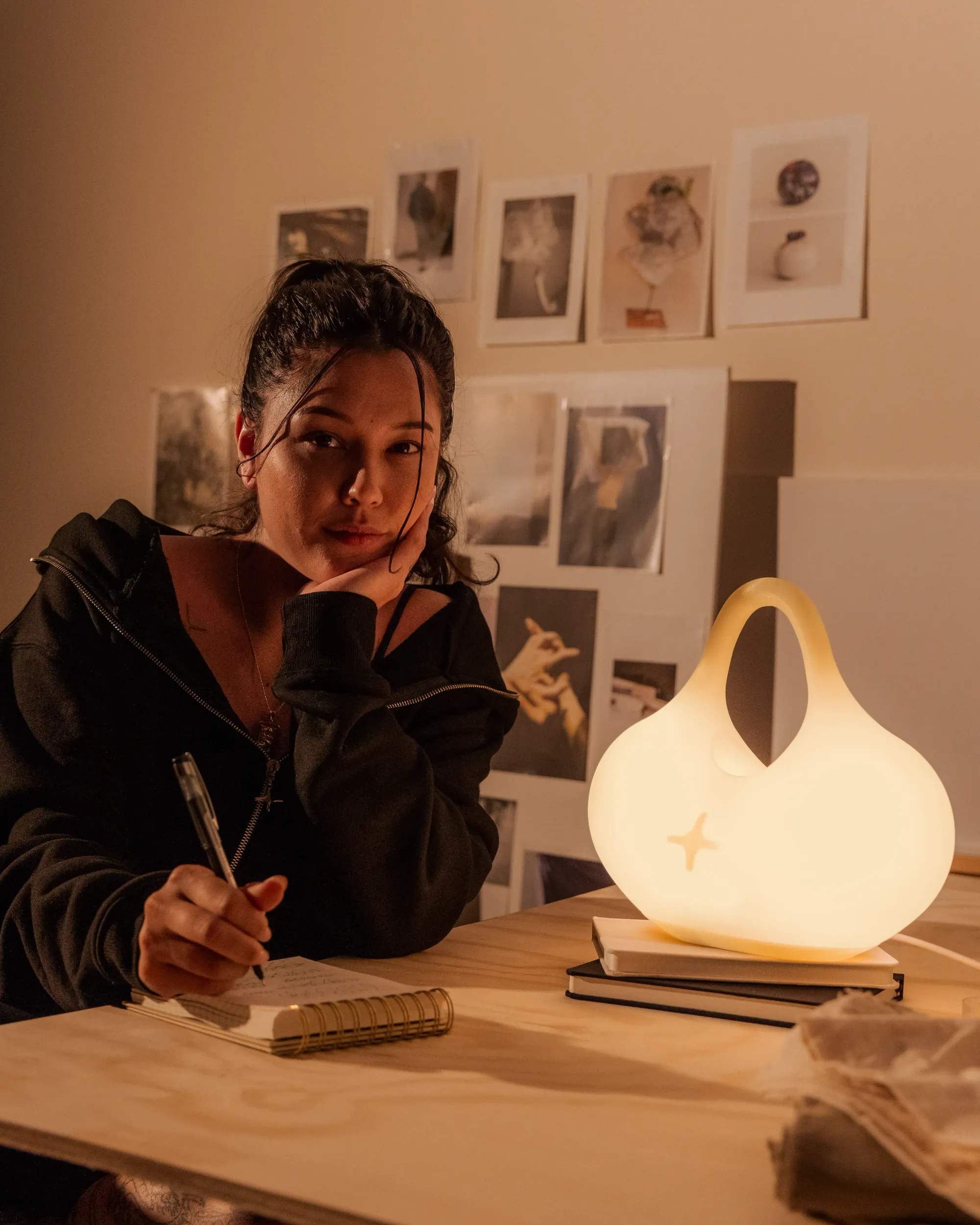 A woman is writing on her small notebook. Her profile is illuminated by light from a Gantri Bag Table Light.