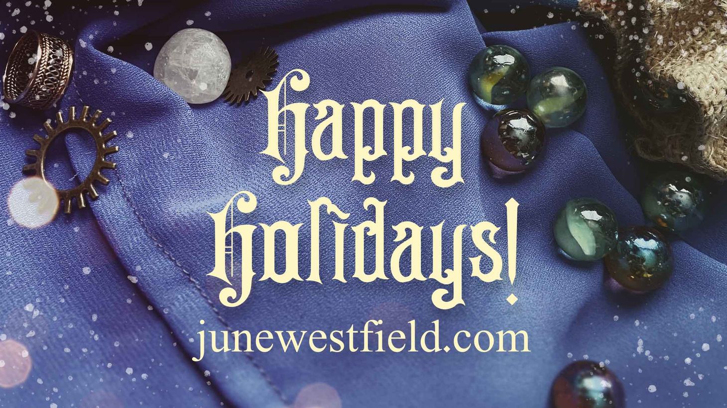 'Happy Holidays!' over a blue cloth background decorated with marbles, crystals, and gears