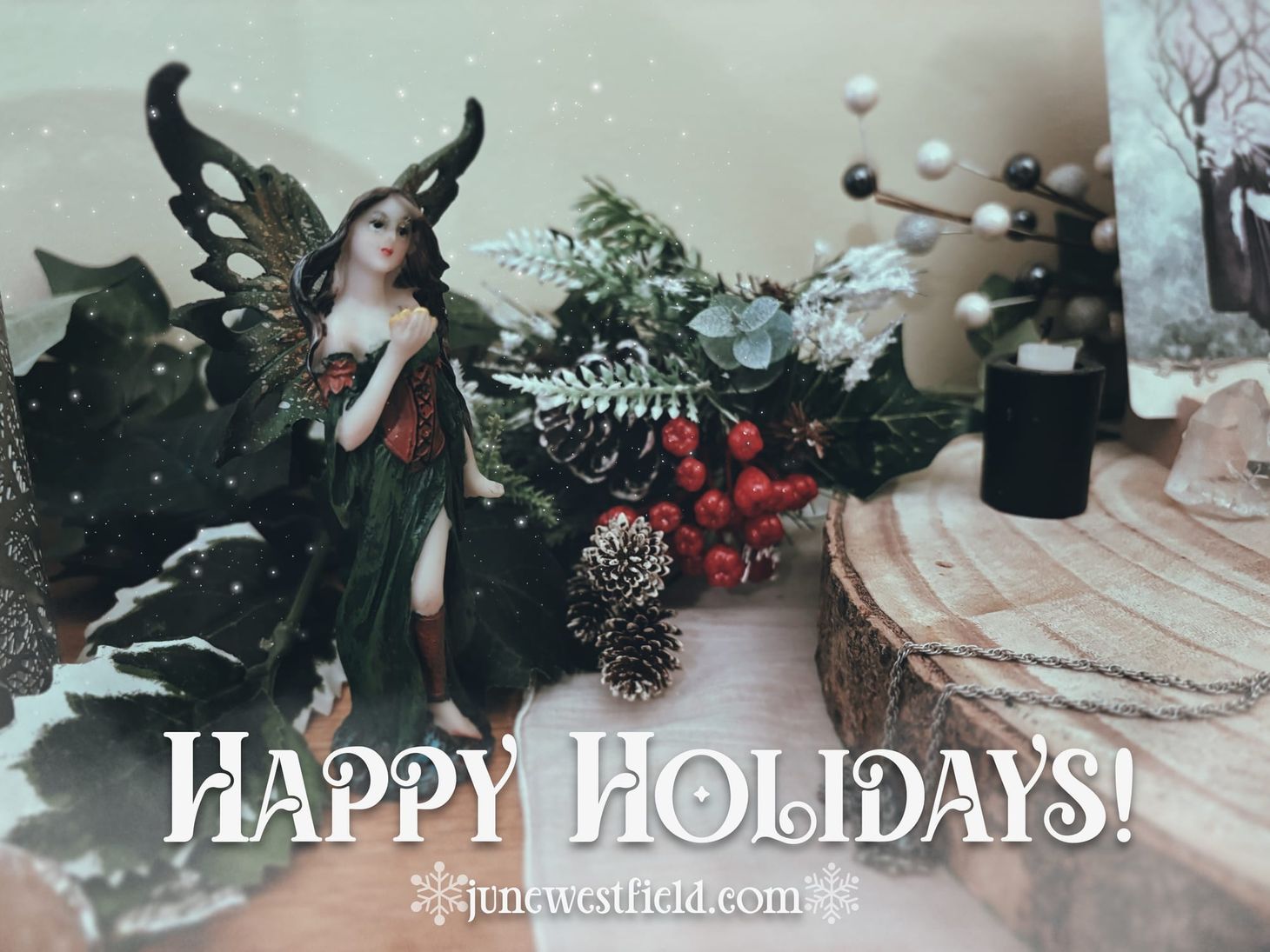 Photo of a small fairy statue amongst holiday greenery, overlayed by the text Happy Holidays! junewestfield.com