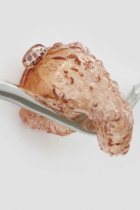 a sculpture of lumpy glass, melting over a steel rod