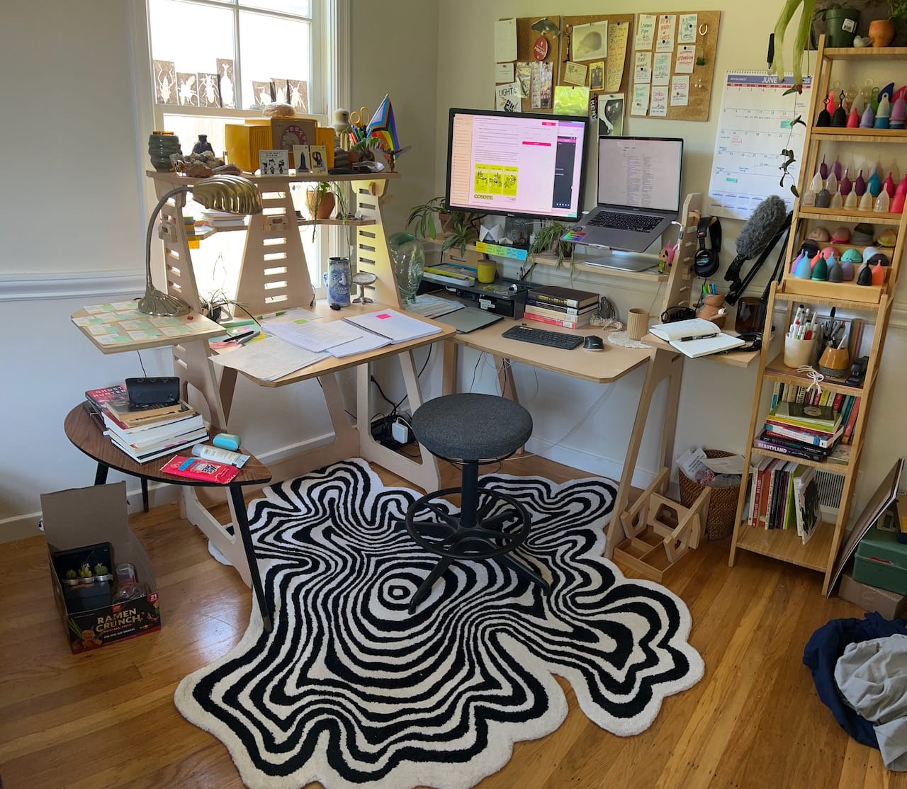 a photo of an L desk with a weird striped rug and a lot of stuff hanging on the walls