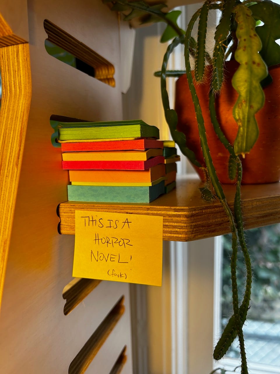 A post it note stuck to my desk that says "this is a horror novel! fuck"