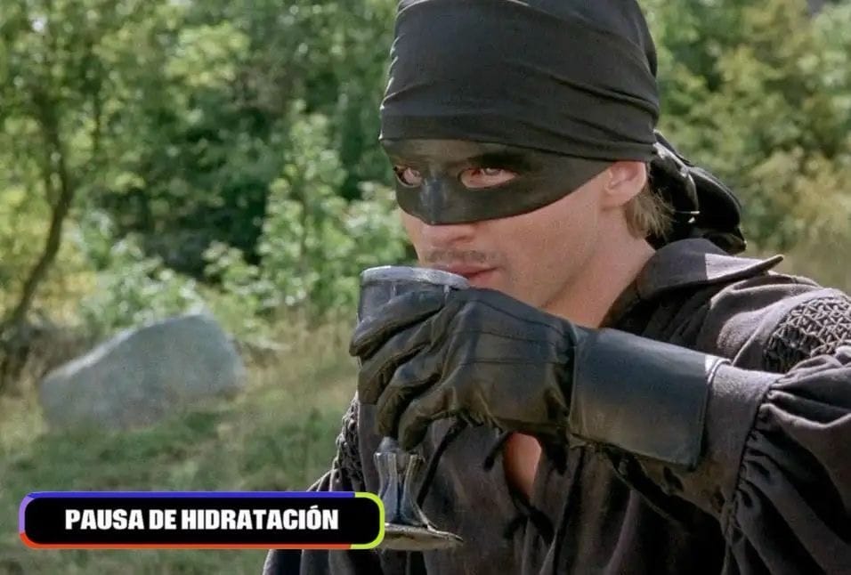 A still from The Princess Bride where the man in black (wearing all black, black gloves, and a black mask) drinks from a cup, and the chyron says "Pausa De Hidratacion"