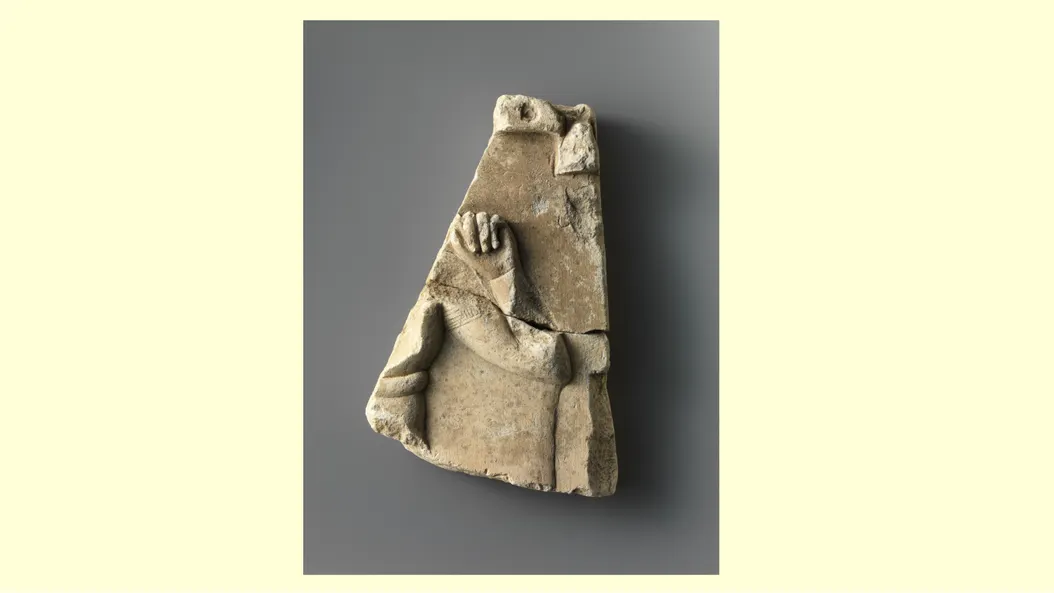 a small clay tablet showing a little hand making a fist