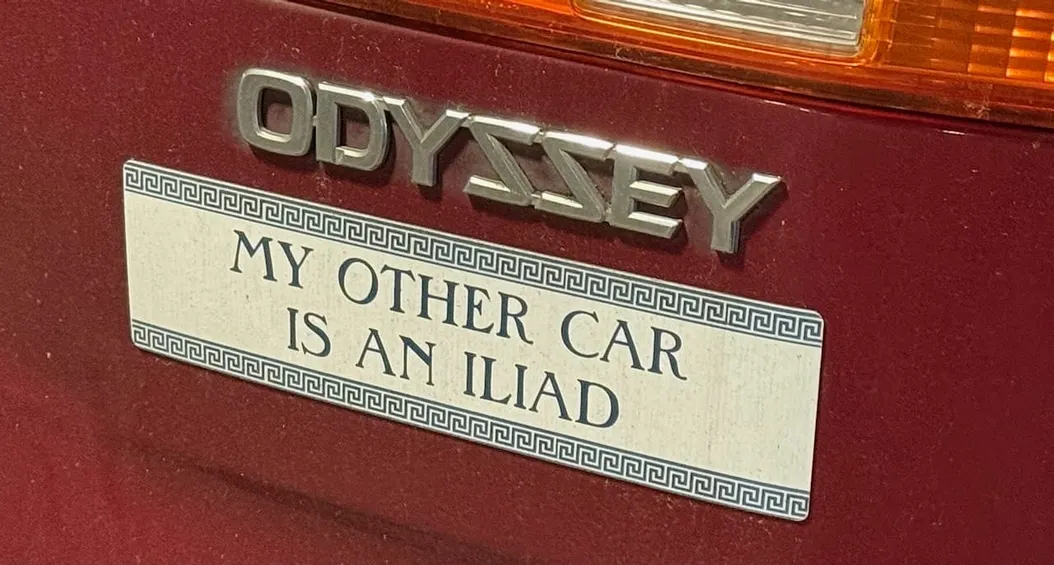 a photograph of a Honda Odyssey logo, beneath which is a sticker that says "my other car is an Iliad"