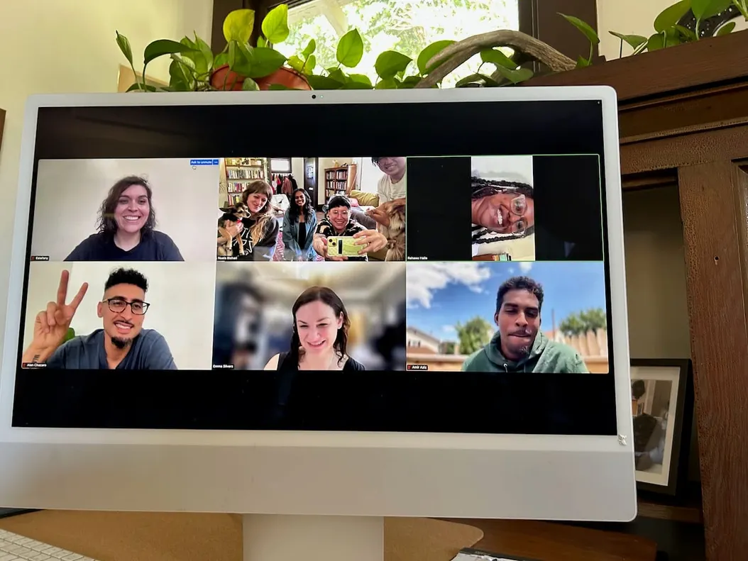 a photo of a computer that has several people on screen, and in one box four people and two dogs