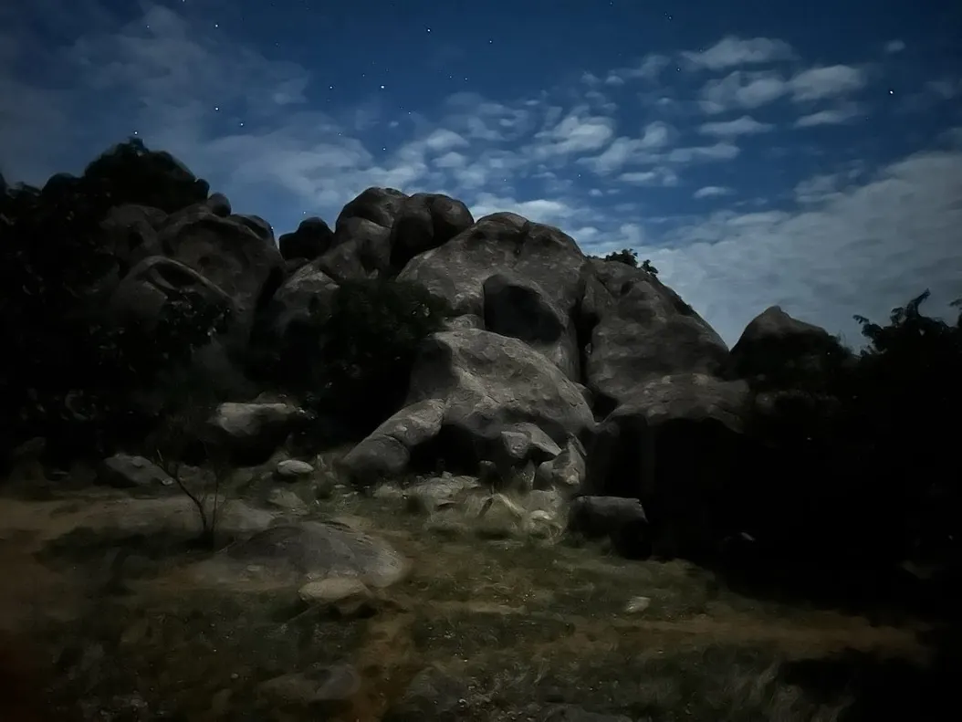 A blurry, almost painting like photo of a set of rocks and a muted blue sky with stars in it.