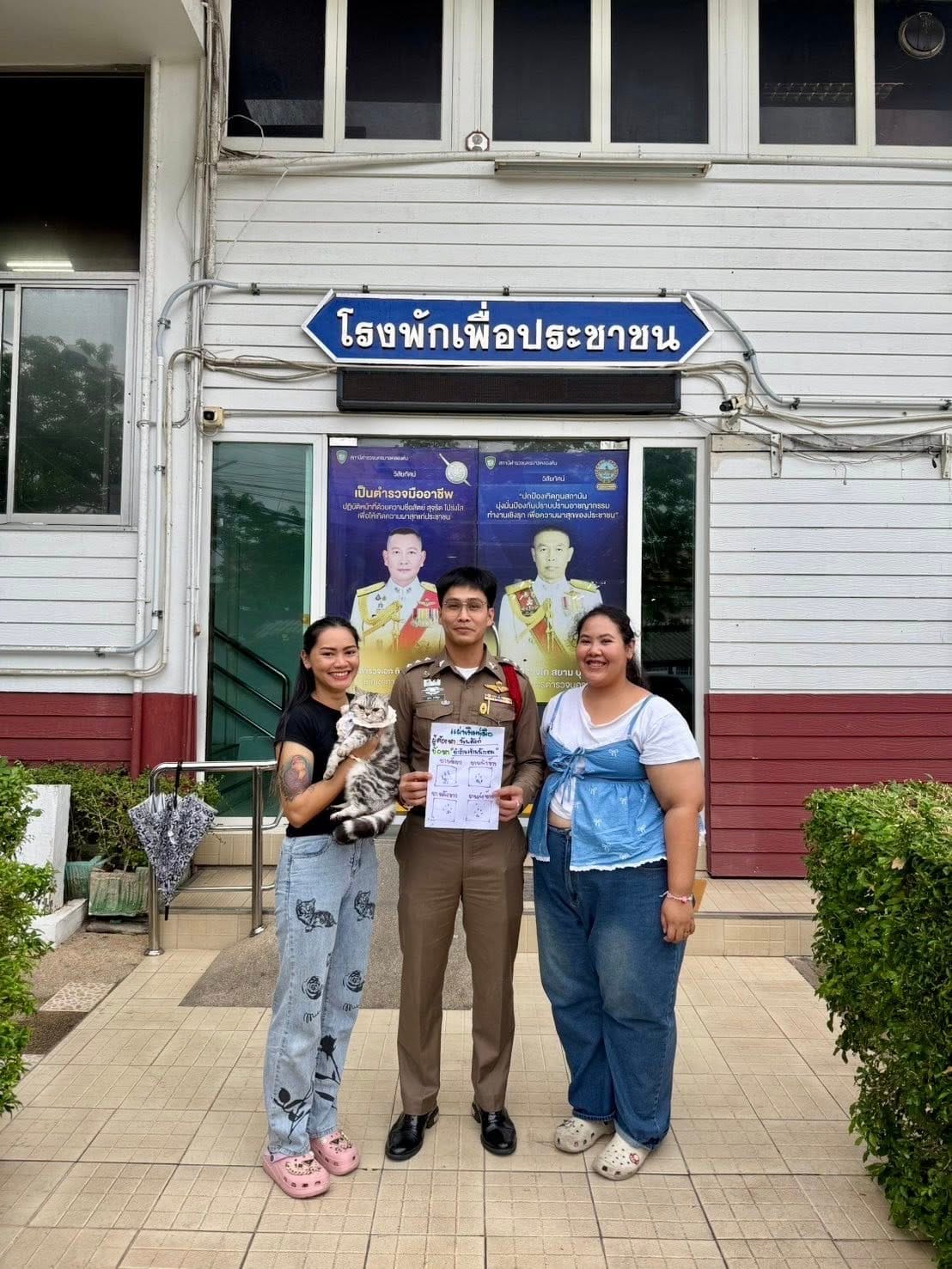A picture of Nub Tang, the police rescuer, and Nub Tang's owners in front the police station door.