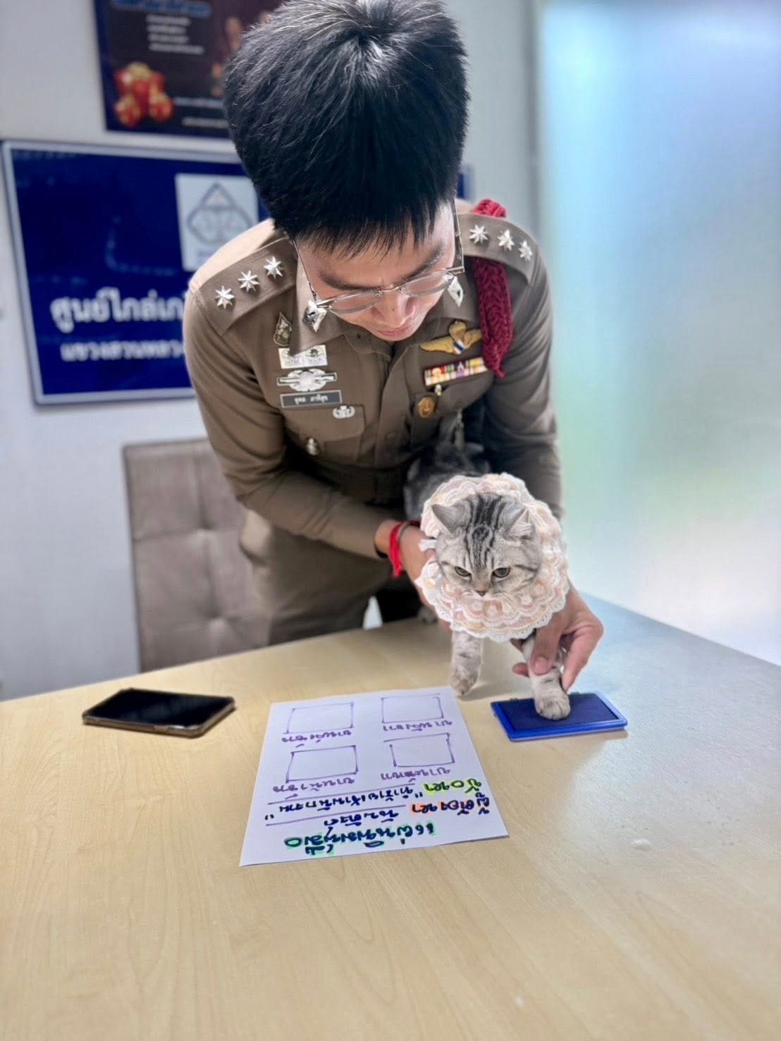 Police officer is holding Nub Tang to take paw prints.