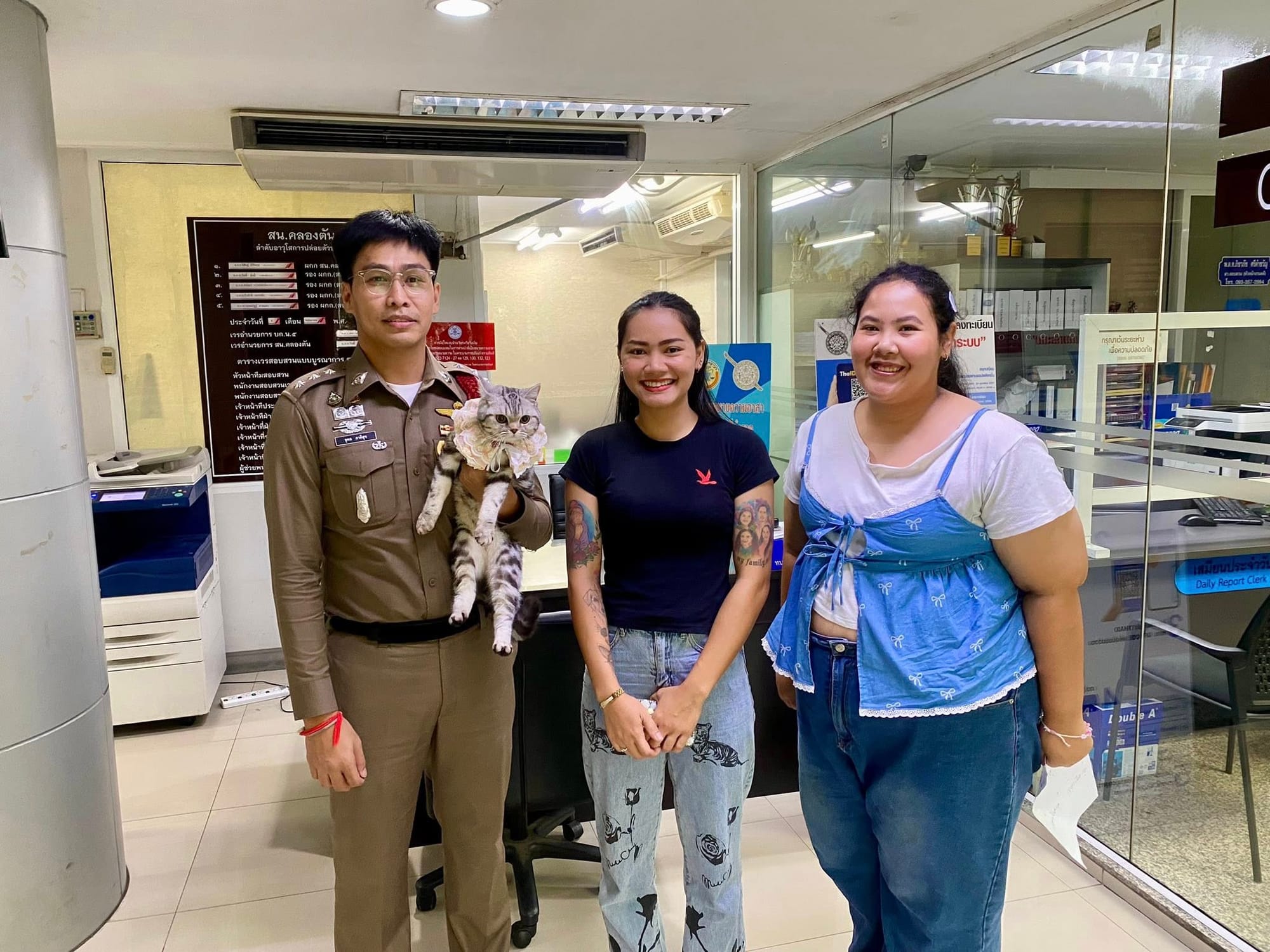 A picture of Nub Tang, the police rescuer, and Nub Tang's owners inside the police station.