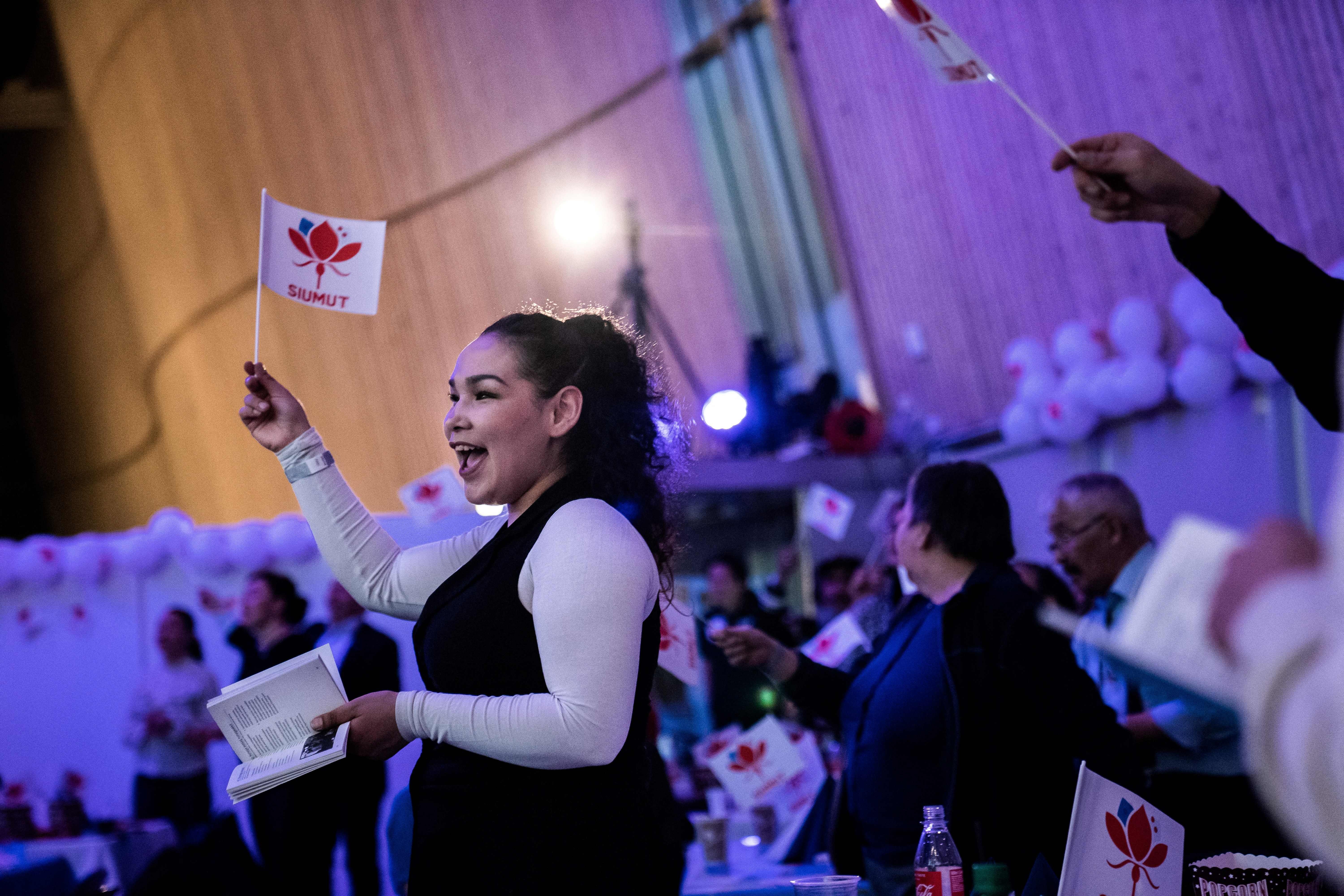 Members of the Siumut party wave party flags as they celebrate following the exit polls results of the legislative election photo.