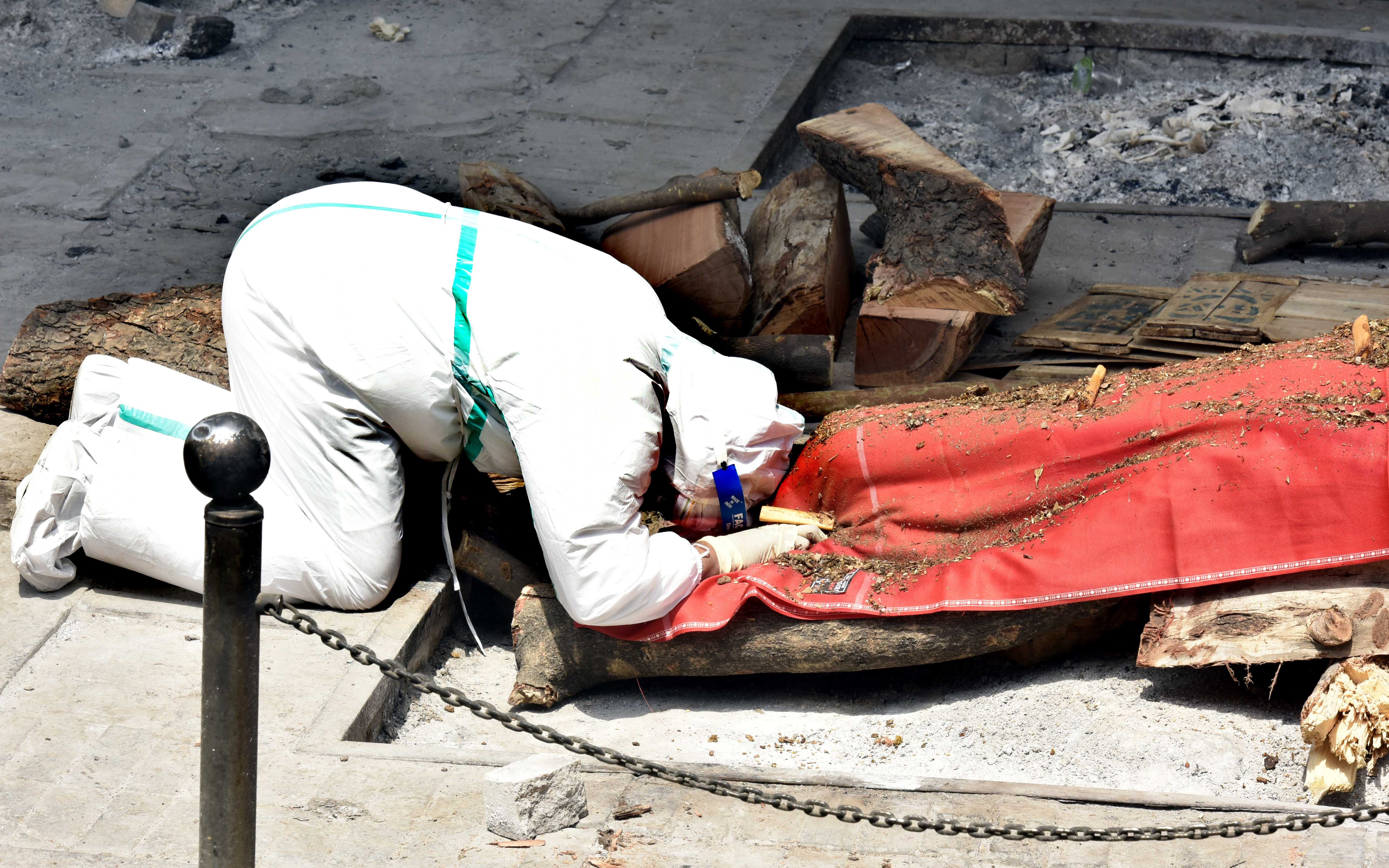 Relatives of a person who died of Covid-19 perform the last rites during cremation at Nigambodh Ghat Crematorium in New Delhi, India.