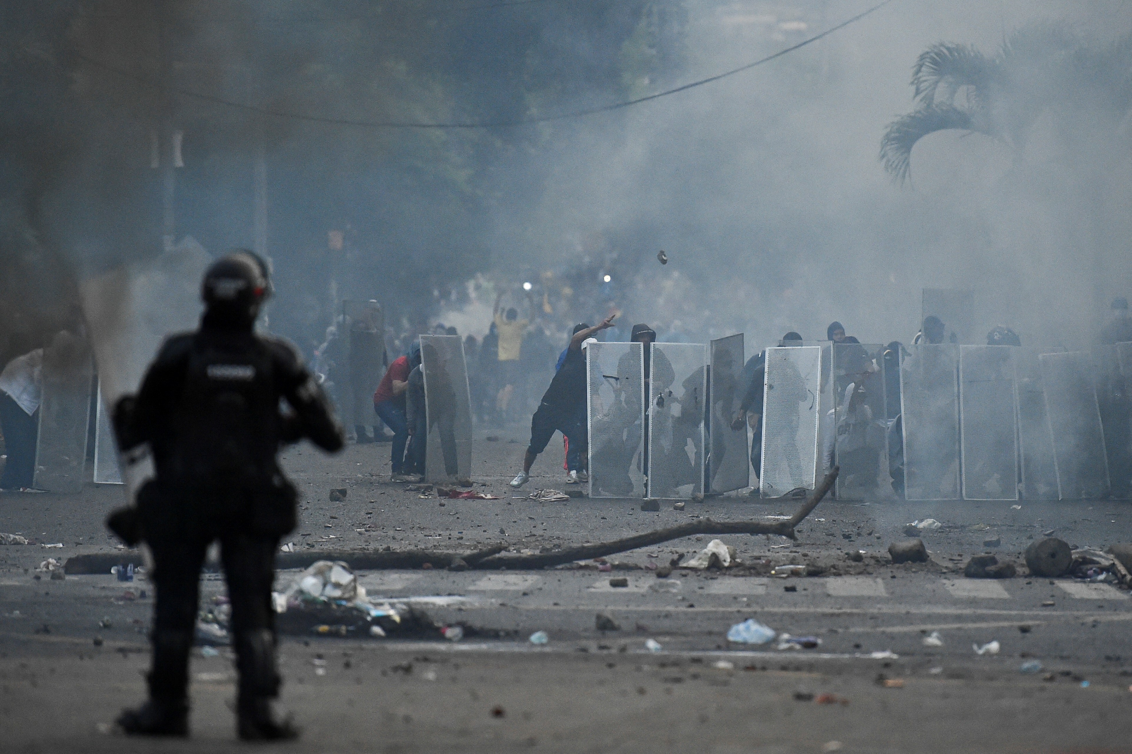 Demonstrators take cover behind makeshift shields during clashes with riot police officers following a protest against a tax reform bill launched by President Ivan Duque, in Cali, Colombia.