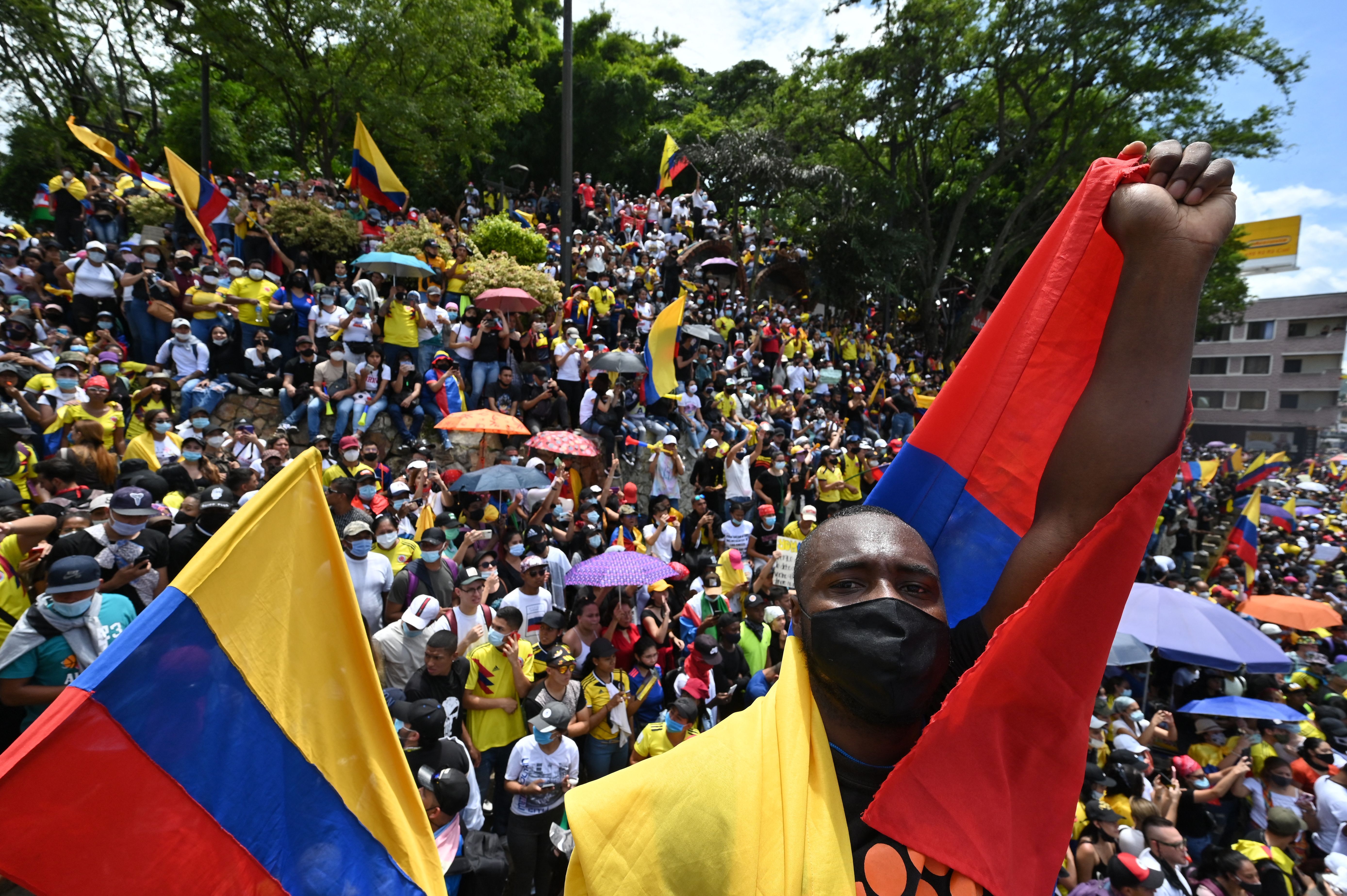 People hold a sign reading Democracy is not in quarantine during protest against a tax reform bill they say will leave them poorer as the country battles its deadliest phase yet of the coronavirus pandemic, in Cali, Colombia.